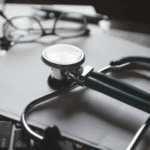 A stethoscope placed on a sheet of paper, lying on a computer keyboard
